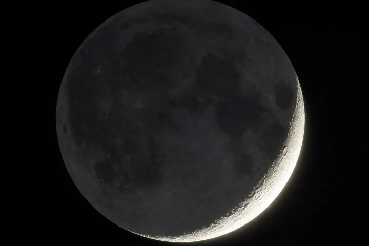 La falce di Luna con la luce cinerea che illumina debolmente il resto del disco lunare, fotografico realistico